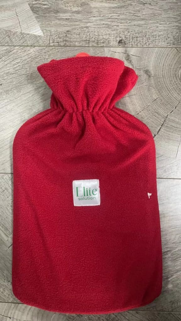 A Red Flannel Thermal Container Designed For Heat Therapy And Warming, Made By Elite Solution. The Elite Hot Water Bottle. Elite Hot Water Bag